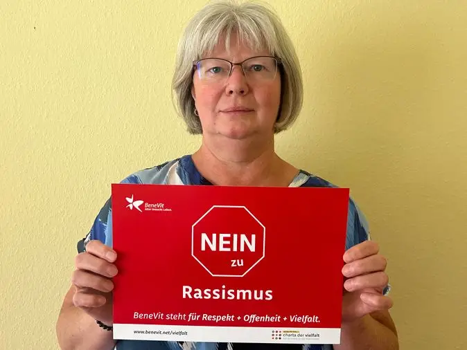 BeneVit Mitarbeiterin mit Plakat gegen Rassismus