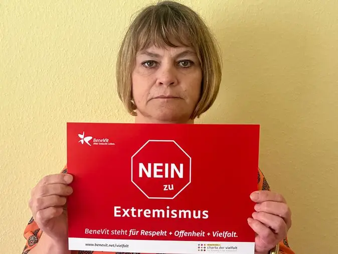 BeneVit Mitarbeiterin mit Plakat gegen Extremismus