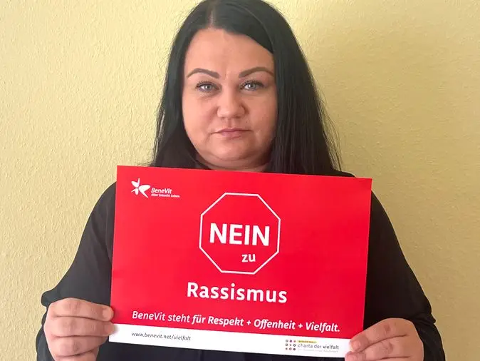 BeneVit Mitarbeiterin mit Plakat gegen Rassismus