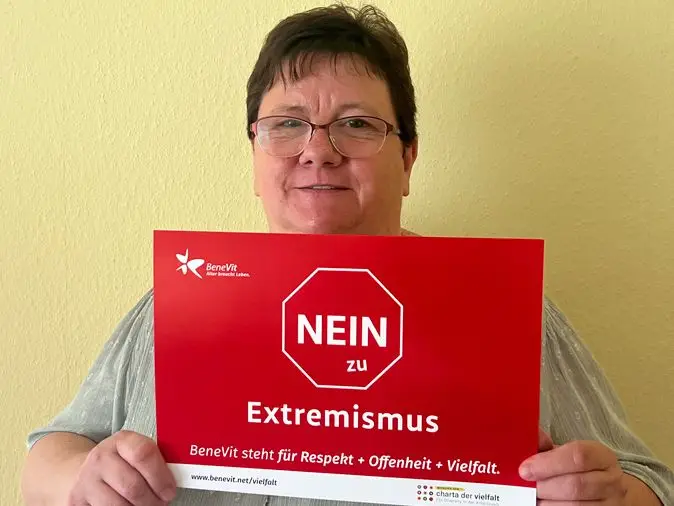 BeneVit Mitarbeiterin mit Plakat gegen Extremismus