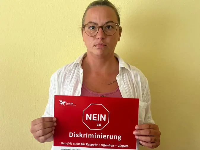 BeneVit Mitarbeiterin mit Plakat gegen Diskriminierung