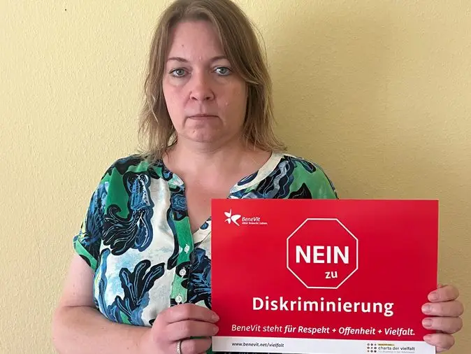 BeneVit Mitarbeiterin mit Plakat gegen Diskriminierung
