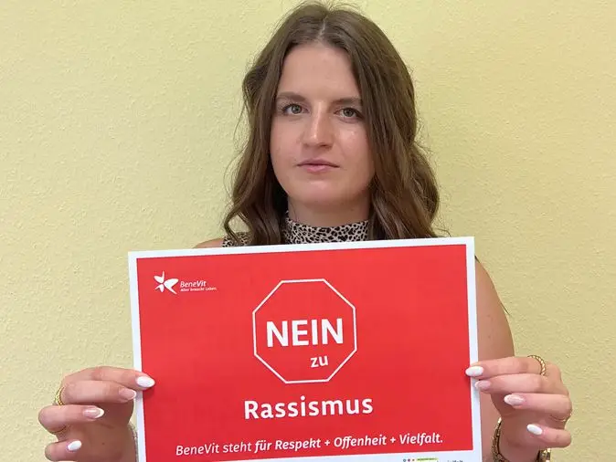 BeneVit Mitarbeiterin mit Plakat gegen Rassismus