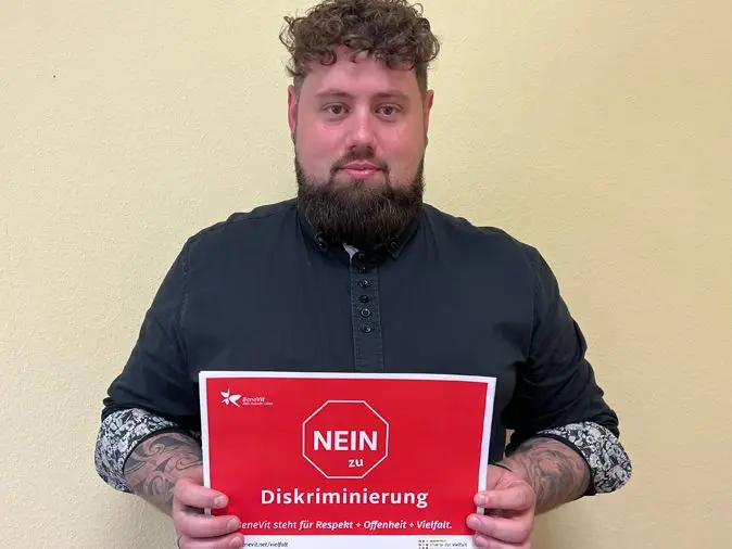 BeneVit Mitarbeiter mit Plakat gegen Diskriminierung