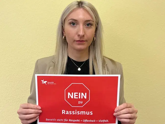 BeneVit Mitarbeiterin mit Plakat gegen Rassismus