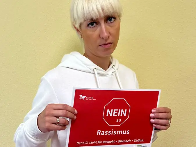 BeneVit Mitarbeiterin mit Plakat gegen Rassismus