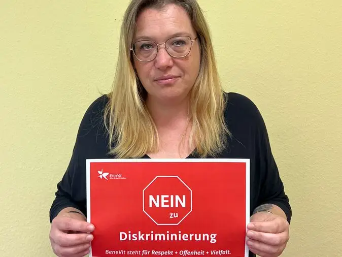 BeneVit Mitarbeiterin mit Plakat gegen Diskriminierung