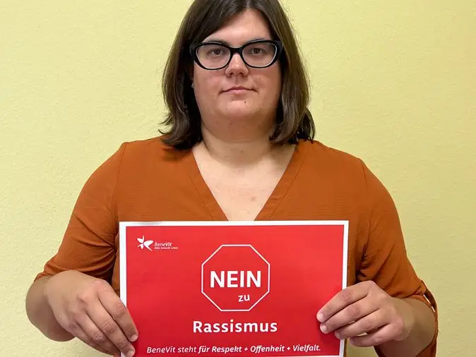 BeneVit Mitarbeiterin mit Plakat gegen Rassismus