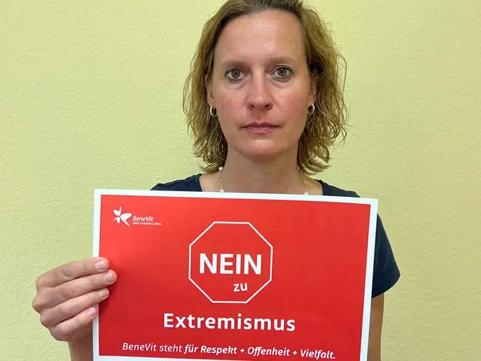 BeneVit Mitarbeiterin mit Plakat gegen Extremismus