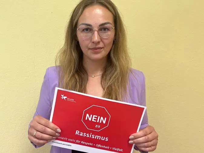BeneVit Mitarbeiterin mit Plakat gegen Rassismus