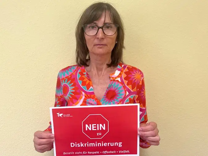 BeneVit Mitarbeiterin mit Plakat gegen Diskriminierung