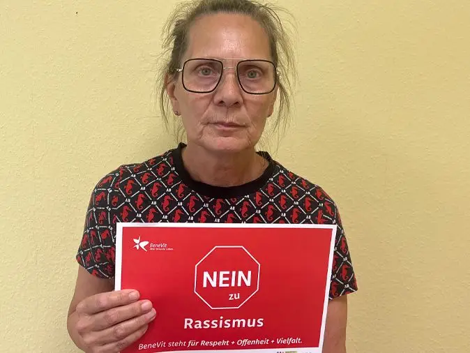 BeneVit Mitarbeiterin mit Plakat gegen Rassismus