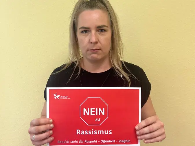 BeneVit Mitarbeiterin mit Plakat gegen Rassismus