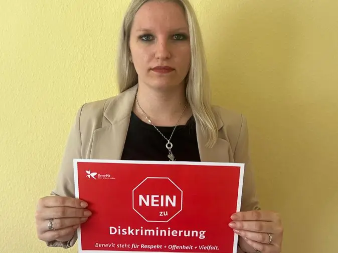 BeneVit Mitarbeiterin mit Plakat gegen Diskriminierung