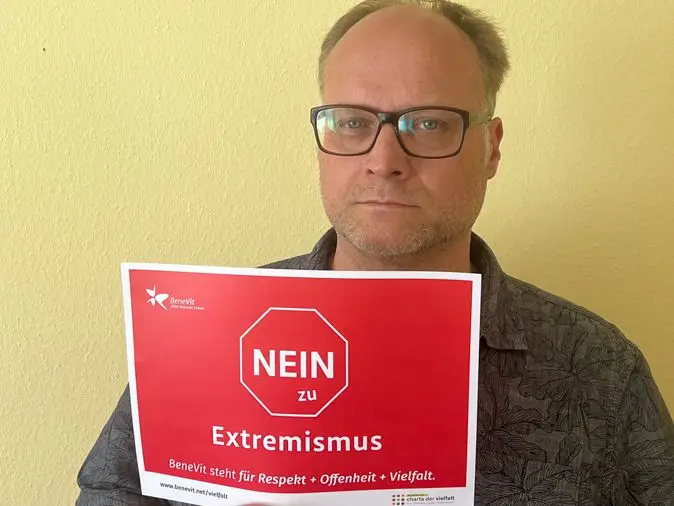 BeneVit Mitarbeiter mit Plakat gegen Extremismus