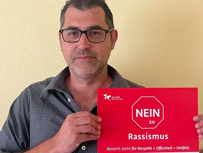 BeneVit Mitarbeiter mit Plakat gegen Rassismus